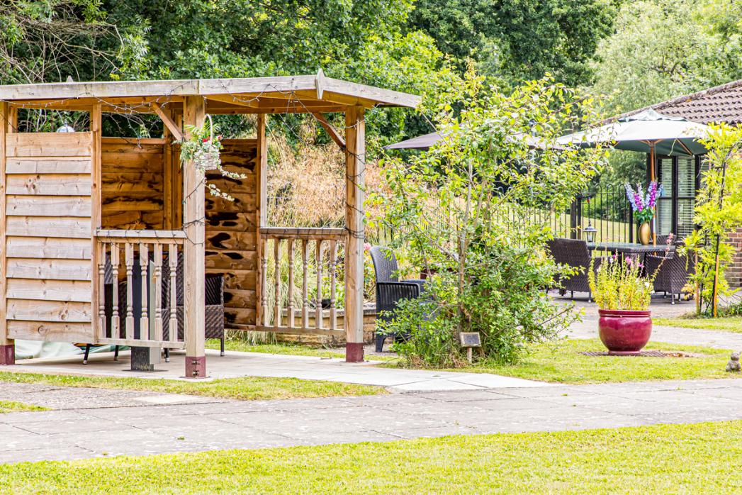 wooden shelter in garden with string lights and seating